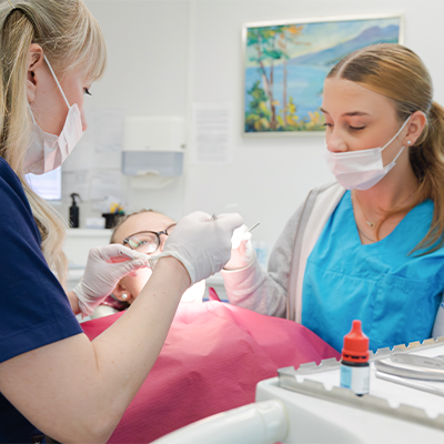 Zahnarzt und zahnärztliche Assistentin behandeln ein junges Mädchen – kinderfreundliche Zahnbehandlung und professionelle Betreuung.
