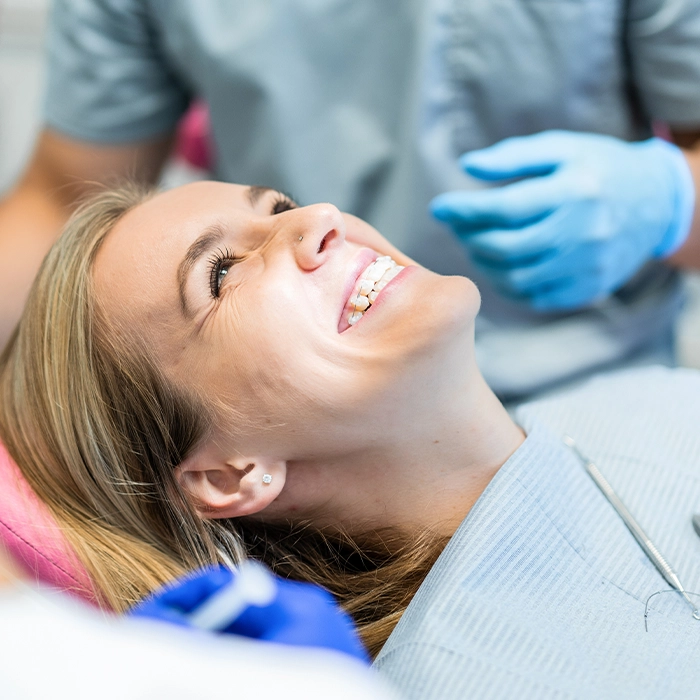Lächelnde Frau liegt auf dem Zahnarztstuhl nach einer Botox-Behandlung bei CMD (Craniomandibuläre Dysfunktion) – entspannte Kiefermuskulatur und verbesserter Komfort.